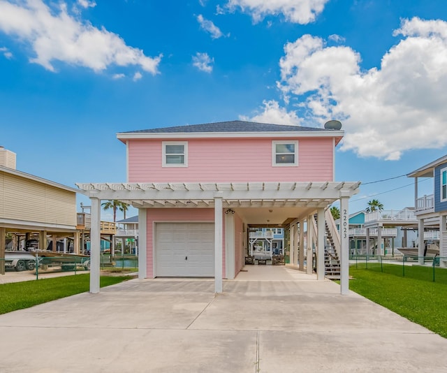 22023 Deaf P Smith Dr, Galveston, TX 77554 - view of front facade featuring a carport, an attached garage, driveway, a front lawn, and a pergola