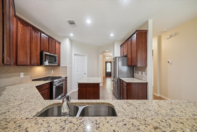 5023 Birch Manor Ln, Katy, TX 77494 - kitchen with stainless steel appliances, a sink, arched walkways, decorative backsplash, and baseboards