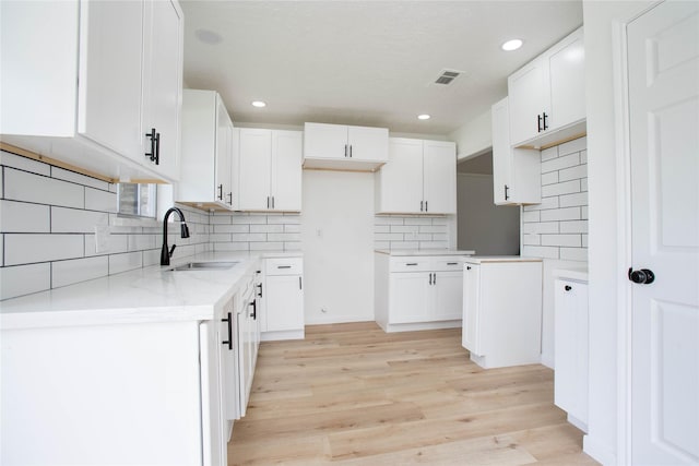 29302 Raestone St, Spring, TX 77386 - kitchen with a sink, decorative backsplash, light wood-type flooring, light stone counters, and white cabinets