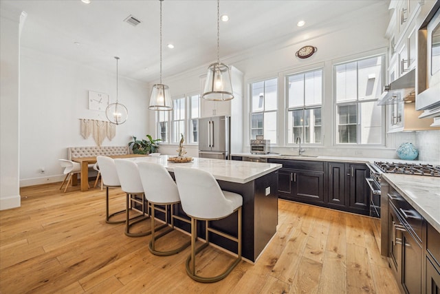 6110 Nicholas Grove Pl, Houston, TX 77055 - kitchen with high end appliances, a kitchen island, a breakfast bar area, light stone counters, and recessed lighting