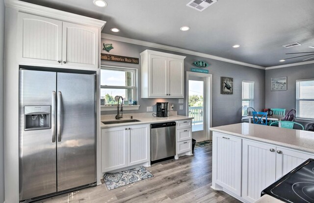 948 Holiday, Crystal Beach, TX 77650 - kitchen with appliances with stainless steel finishes, a sink, crown molding, white cabinets, and light countertops