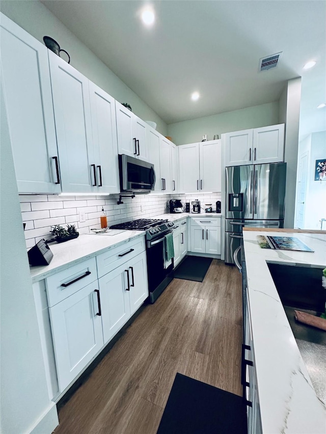 210 E 39th St, Houston, TX 77018 - kitchen featuring appliances with stainless steel finishes, light stone countertops, white cabinetry, and recessed lighting