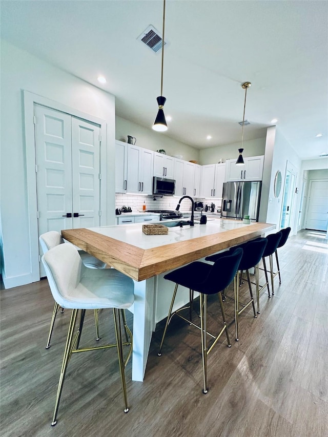 210 E 39th St, Houston, TX 77018 - kitchen featuring appliances with stainless steel finishes, wood finished floors, white cabinets, a sink, and recessed lighting