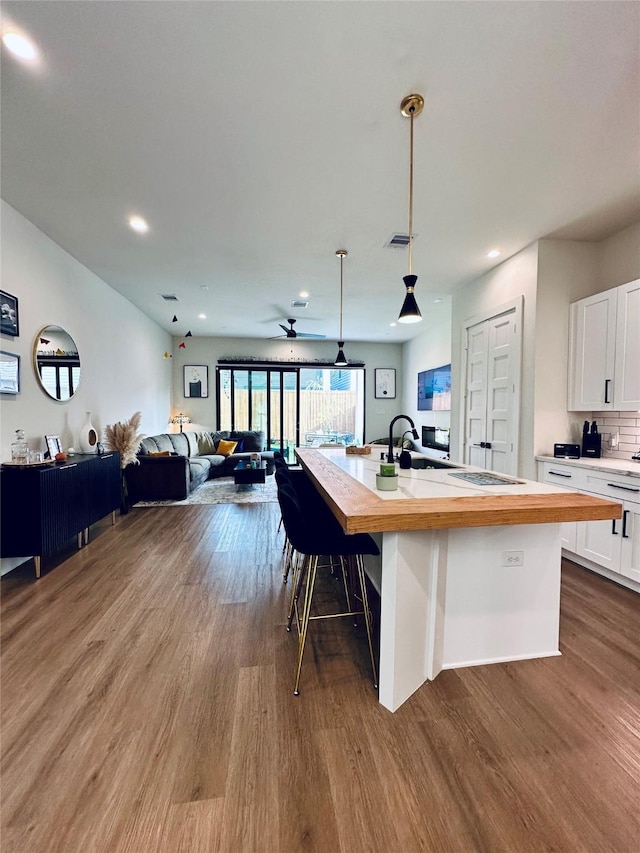 210 E 39th St, Houston, TX 77018 - kitchen with open floor plan, dark wood finished floors, an island with sink, white cabinets, and butcher block counters