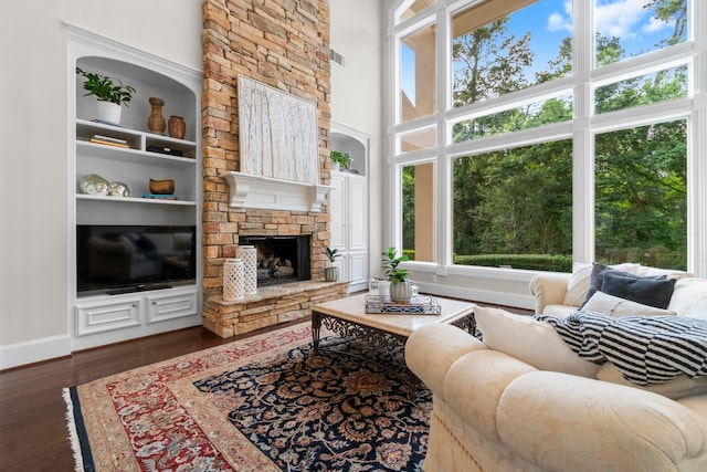 91 N Hunters Crossing Cir, The Woodlands, TX 77381 - living area with healthy amount of natural light, wood finished floors, a stone fireplace, a towering ceiling, and baseboards