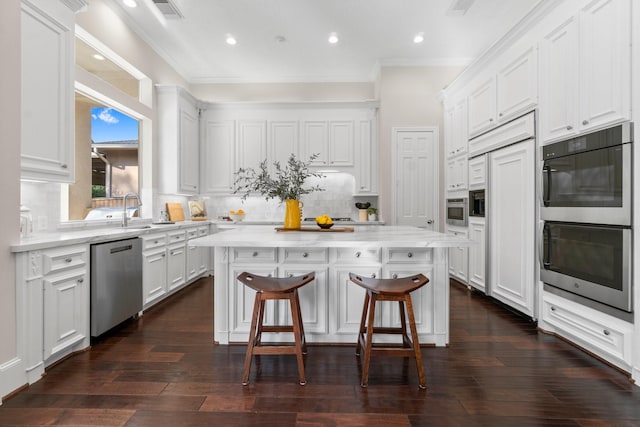 91 N Hunters Crossing Cir, The Woodlands, TX 77381 - kitchen with appliances with stainless steel finishes, a kitchen island, a kitchen breakfast bar, white cabinets, and tasteful backsplash