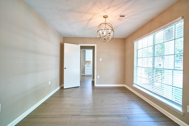11706 Mclain Blvd, Houston, TX 77071 - spare room with a chandelier, healthy amount of natural light, baseboards, wood finished floors, and a textured ceiling