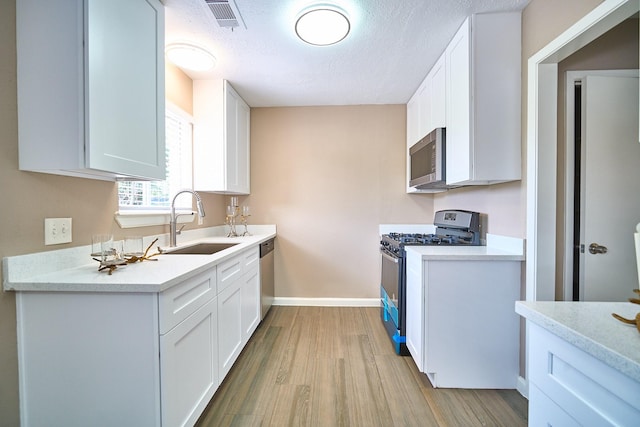 11706 Mclain Blvd, Houston, TX 77071 - kitchen featuring stainless steel appliances, a sink, light wood-type flooring, baseboards, and light countertops