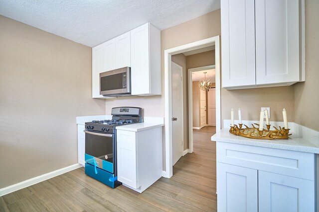 11706 Mclain Blvd, Houston, TX 77071 - kitchen with stainless steel appliances, light wood-style flooring, a chandelier, light countertops, and baseboards