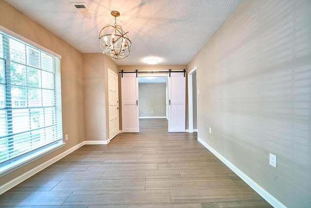 11706 Mclain Blvd, Houston, TX 77071 - unfurnished room featuring a chandelier, a barn door, baseboards, wood finished floors, and a textured ceiling