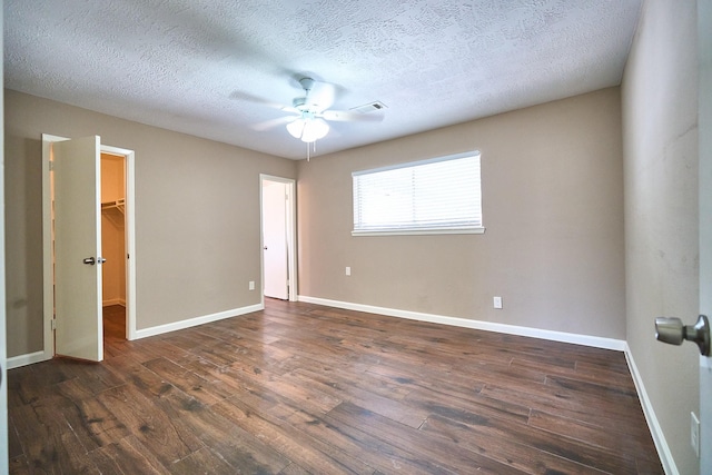 11706 Mclain Blvd, Houston, TX 77071 - unfurnished bedroom with a spacious closet, dark wood finished floors, baseboards, a ceiling fan, and a textured ceiling