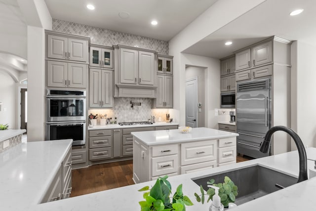 28911 Ally Lynn Way, Katy, TX 77494 - kitchen featuring built in appliances, gray cabinets, a sink, dark wood finished floors, and glass insert cabinets