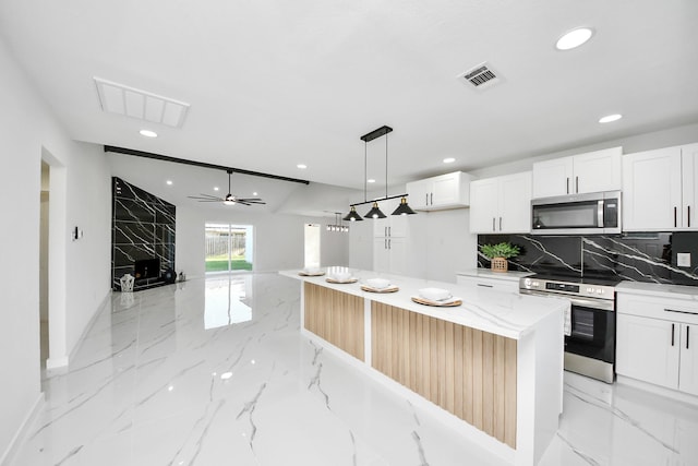 22718 Carter Moir Ln, Katy, TX 77449 - kitchen with appliances with stainless steel finishes, recessed lighting, light marble finish floors, white cabinetry, and decorative backsplash