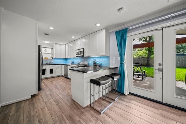 3010 Helberg Rd, Houston, TX 77092 - kitchen with appliances with stainless steel finishes, a peninsula, white cabinets, light wood-type flooring, and recessed lighting