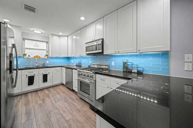 3010 Helberg Rd, Houston, TX 77092 - kitchen with appliances with stainless steel finishes, a sink, backsplash, dark countertops, and a textured wall