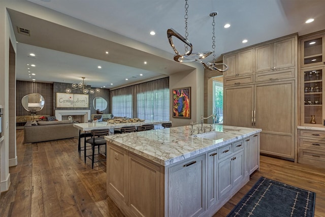 3637 Meadow Lake Ln, Houston, TX 77027 - kitchen featuring a chandelier, a kitchen island with sink, a sink, dark wood finished floors, and light stone countertops