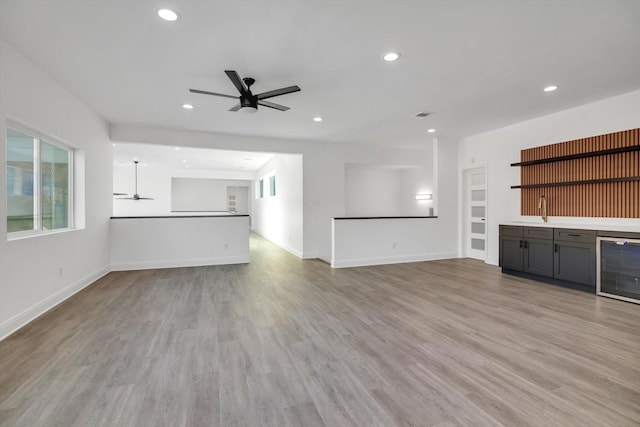 12564 Memorial Dr, Houston, TX 77024 - unfurnished living room with beverage cooler, a ceiling fan, a bar, recessed lighting, and light wood-type flooring