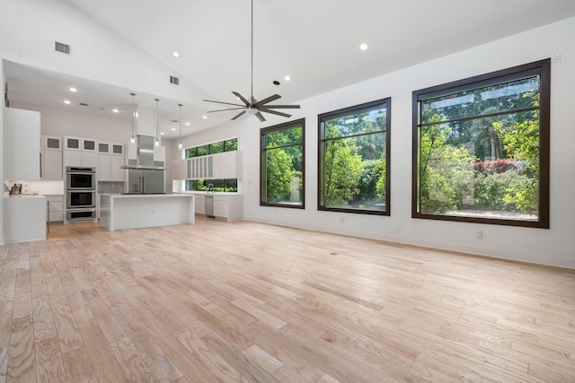 16827 Falcon Sound Dr, Montgomery, TX 77356 - unfurnished living room featuring healthy amount of natural light, light wood finished floors, recessed lighting, ceiling fan, and high vaulted ceiling