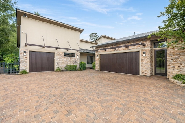 16827 Falcon Sound Dr, Montgomery, TX 77356 - view of front facade featuring stone siding, decorative driveway, a standing seam roof, a garage, and metal roof
