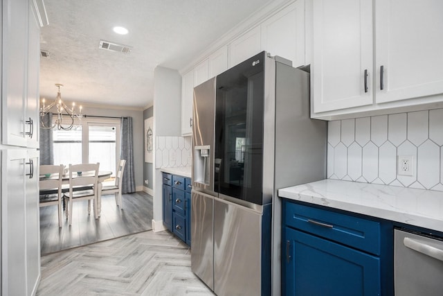 5720 Fraser Ave, Galveston, TX 77551 - kitchen featuring blue cabinetry, stainless steel appliances, a chandelier, a textured ceiling, and white cabinetry