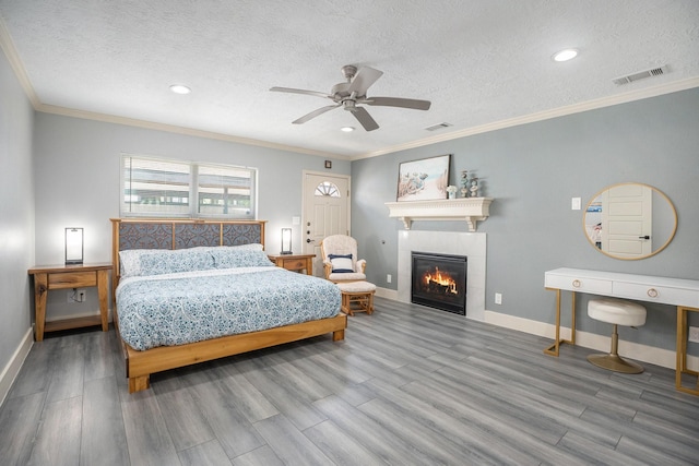 5720 Fraser Ave, Galveston, TX 77551 - bedroom featuring wood finished floors, ornamental molding, a textured ceiling, a fireplace, and baseboards