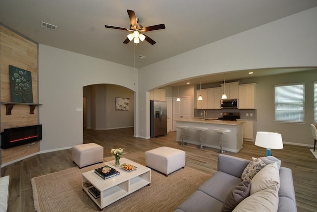 426 Sunny River Ln, Richmond, TX 77406 - living room featuring arched walkways, ceiling fan, wood finished floors, a fireplace, and baseboards