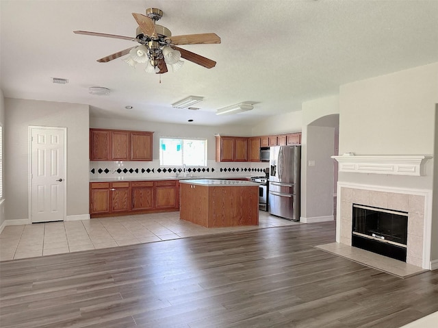 15318 Griggs Point Ln, Sugar Land, TX 77498 - kitchen with stainless steel appliances, brown cabinets, light wood finished floors, and decorative backsplash