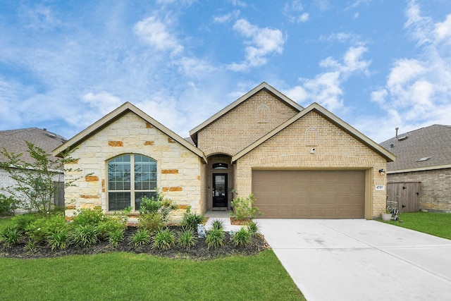 4710 Jasmine Heather Ln, Baytown, TX 77521 - view of front of home featuring brick siding, a garage, concrete driveway, stone siding, and a front yard