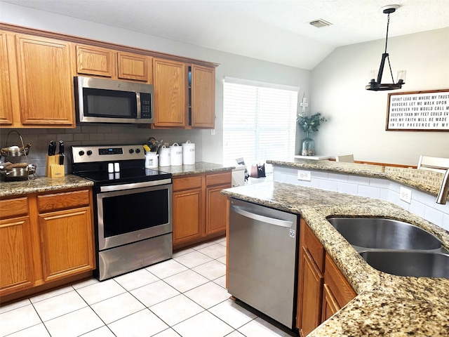 7126 Leens Lodge Ln, Humble, TX 77346 - kitchen featuring appliances with stainless steel finishes, a sink, brown cabinetry, vaulted ceiling, and backsplash
