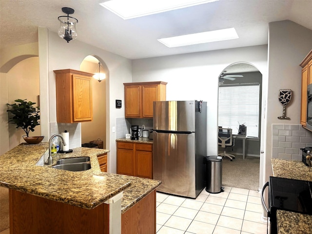 7126 Leens Lodge Ln, Humble, TX 77346 - kitchen featuring freestanding refrigerator, a sink, a skylight, a peninsula, and arched walkways