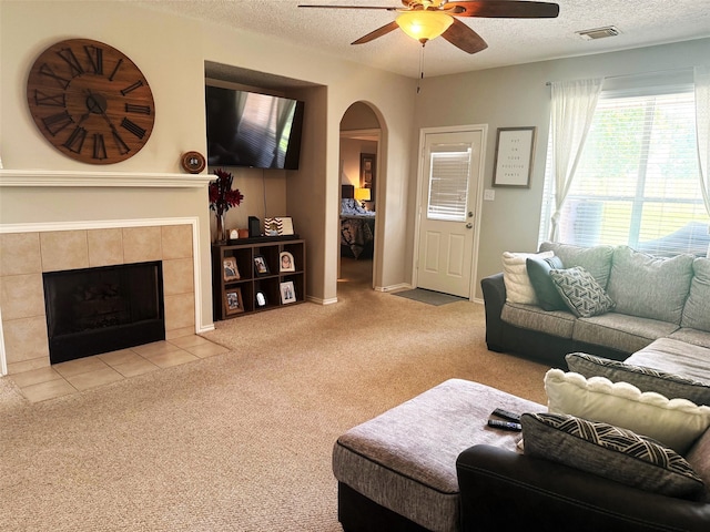 7126 Leens Lodge Ln, Humble, TX 77346 - carpeted living room with ceiling fan, arched walkways, a textured ceiling, and a tile fireplace