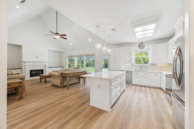 22313 Baneberry Rd, Magnolia, TX 77355 - kitchen with appliances with stainless steel finishes, a sink, white cabinets, a center island, and a fireplace
