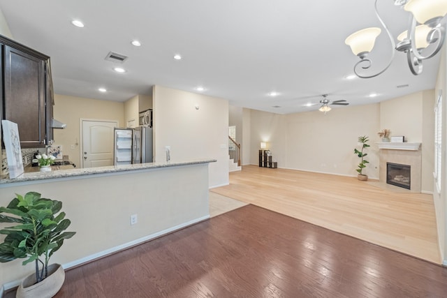 12627 Ashford Shore Dr, Houston, TX 77072 - kitchen with smart refrigerator, light wood-type flooring, ceiling fan, a tile fireplace, and light stone countertops