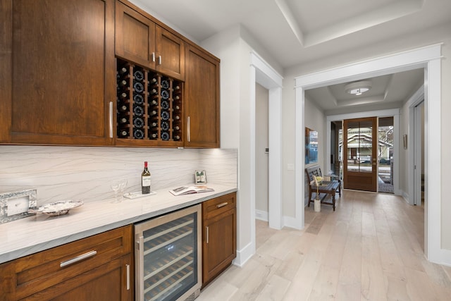 1710 Ebony Ln, Houston, TX 77018 - indoor dry bar with beverage cooler, a tray ceiling, baseboards, light wood-type flooring, and decorative backsplash