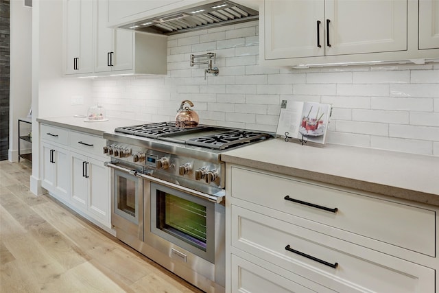 1710 Ebony Ln, Houston, TX 77018 - kitchen featuring range with two ovens, premium range hood, light countertops, light wood-type flooring, and tasteful backsplash