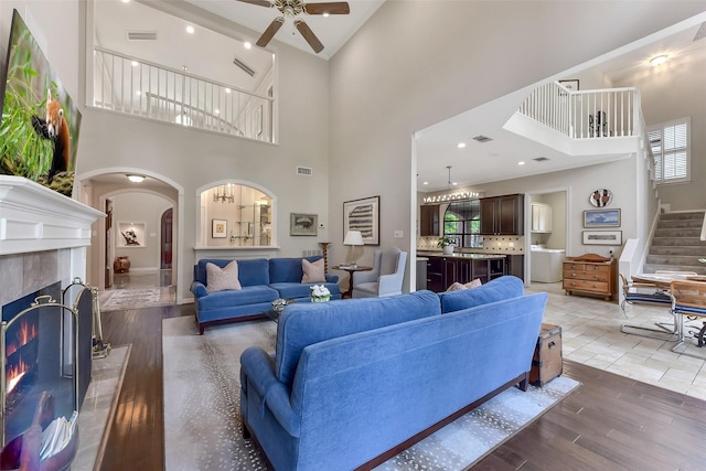 6 Woodsborough Cir, Houston, TX 77055 - living area with arched walkways, ceiling fan, a towering ceiling, wood finished floors, and a tile fireplace