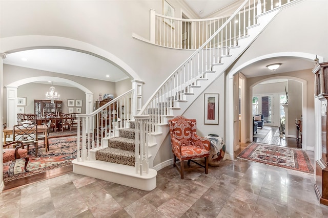 6 Woodsborough Cir, Houston, TX 77055 - foyer entrance featuring arched walkways, a towering ceiling, baseboards, stairs, and a chandelier