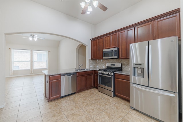 20210 Stonebridge Terrace Dr, Richmond, TX 77407 - kitchen with appliances with stainless steel finishes, a ceiling fan, arched walkways, tasteful backsplash, and light tile patterned floors