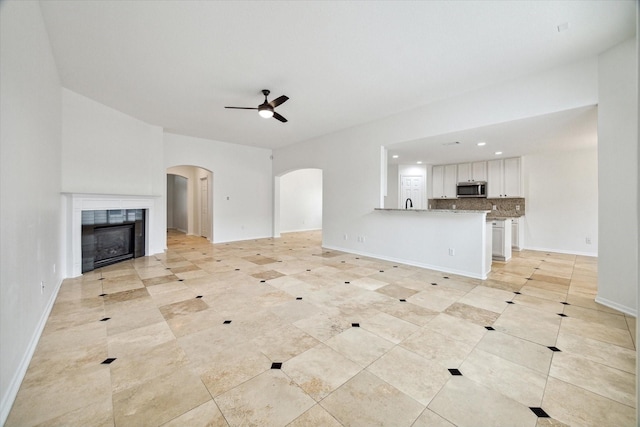 18519 Water Scene Trl, Cypress, TX 77429 - unfurnished living room featuring arched walkways, ceiling fan, a tiled fireplace, light tile patterned floors, and recessed lighting