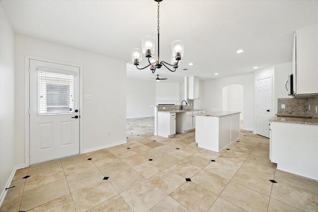 18519 Water Scene Trl, Cypress, TX 77429 - kitchen featuring a chandelier, arched walkways, tasteful backsplash, a kitchen island, and recessed lighting