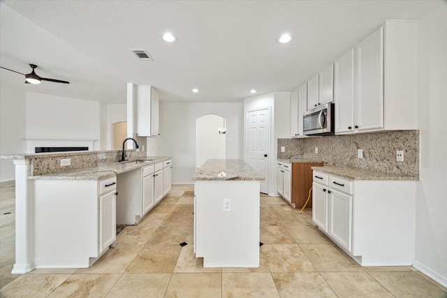 18519 Water Scene Trl, Cypress, TX 77429 - kitchen with a sink, stainless steel microwave, arched walkways, backsplash, and a ceiling fan