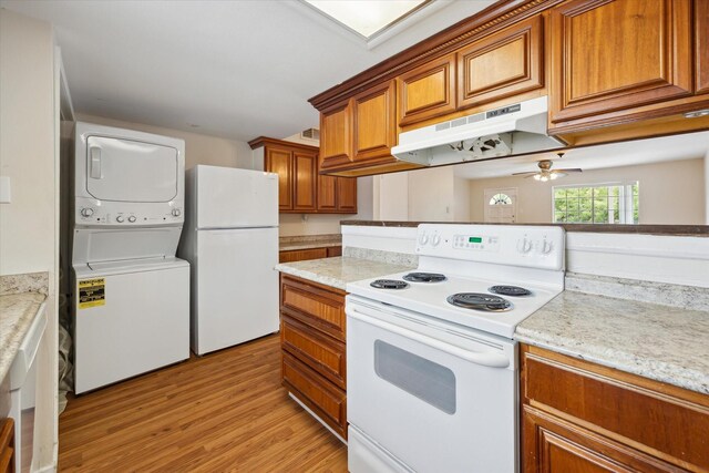 14333 Memorial Dr Unit 72, Houston, TX 77079 - kitchen with white appliances, under cabinet range hood, stacked washer and clothes dryer, brown cabinetry, and light wood-style flooring