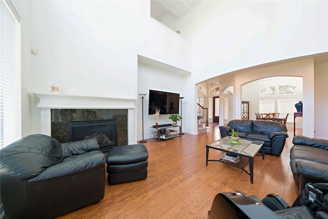 19406 Egret Haven Ln, Cypress, TX 77433 - living room featuring arched walkways, wood finished floors, a fireplace, a towering ceiling, and baseboards