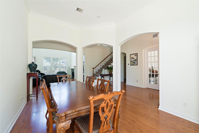 19406 Egret Haven Ln, Cypress, TX 77433 - dining space with arched walkways, light wood finished floors, crown molding, stairs, and baseboards