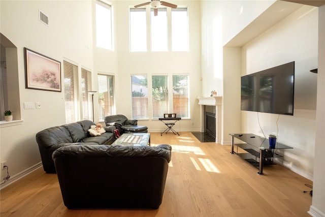 19406 Egret Haven Ln, Cypress, TX 77433 - living area featuring ceiling fan, wood finished floors, arched walkways, a fireplace with flush hearth, and a towering ceiling