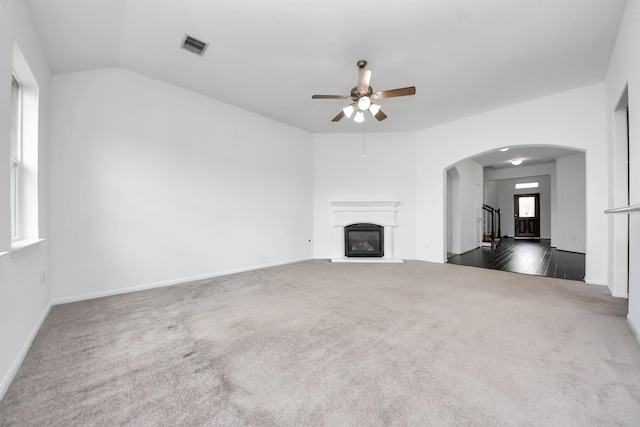 3727 Varna Ct, Missouri City, TX 77459 - unfurnished living room with ceiling fan, dark colored carpet, arched walkways, a glass covered fireplace, and baseboards