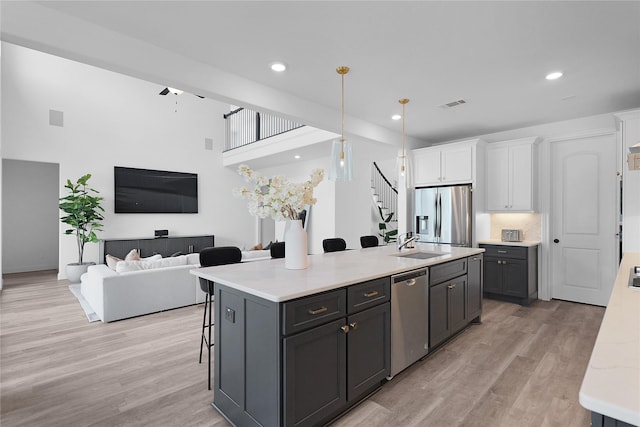 4706 Oak Glen Ct, Manvel, TX 77578 - kitchen with appliances with stainless steel finishes, white cabinetry, light wood-style floors, a kitchen island with sink, and recessed lighting
