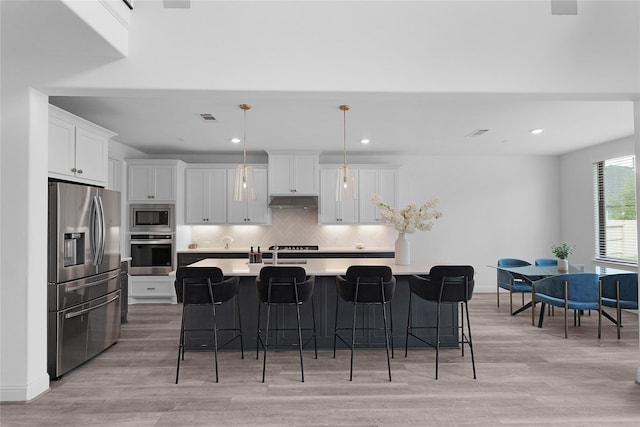 4706 Oak Glen Ct, Manvel, TX 77578 - kitchen with stainless steel appliances, under cabinet range hood, light wood-type flooring, decorative backsplash, and recessed lighting