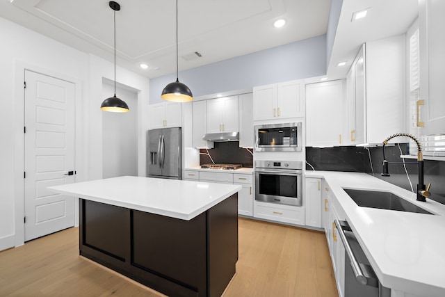 2110 Beall St, Houston, TX 77008 - kitchen with stainless steel appliances, a sink, under cabinet range hood, backsplash, and light wood-style flooring