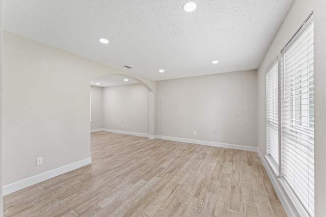 4519 Pioneer Trl, Sugar Land, TX 77479 - spare room featuring light wood-style flooring, a textured ceiling, arched walkways, recessed lighting, and baseboards